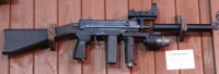 Пистолет-пулемет Skorpion с пластиковым фиксированным прикладом, установленным коллиматорным прицелом, дополнительной рукояткой с тактическим фонарем и прибором бесшумной стрельбы